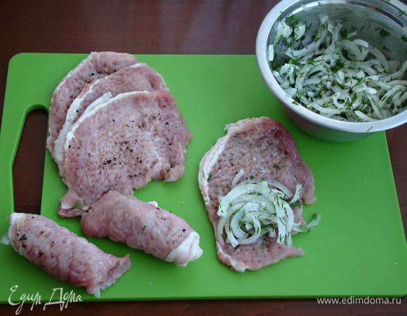 На каждую отбивную положить горсть маринованного лука и свернуть рулетиком.