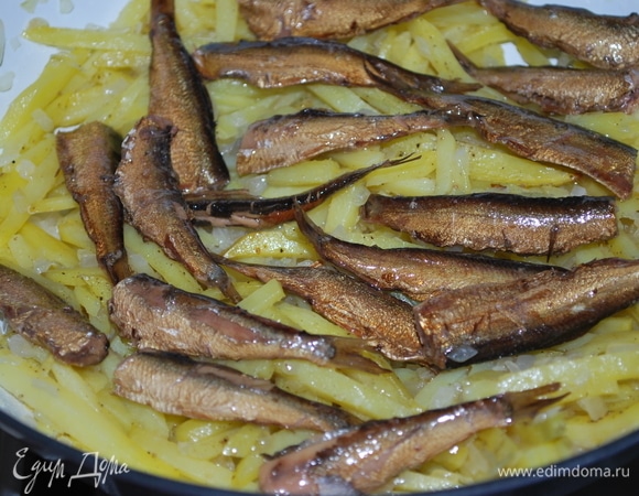 Выложите на дно формы для запекания половину картофеля с луком, сверху разложите одним слоем шпроты. Полейте половиной сливок.