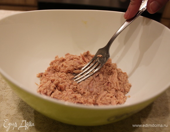 Из банки с консервированным тунцом сливаем всю водичку, выкладываем тунец в миску, вилкой измельчаем.