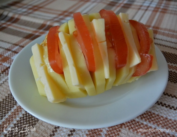 Нарезать картофель не до конца, поочередно положить сыр и помидоры.