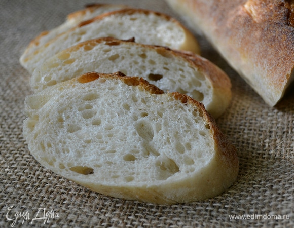 Заготовки перенести на льняную ткань (ткань предварительно натереть мукой) швом вверх. Между каждой заготовкой из ткани сделать складку, накрыть пленкой. Окончательная расстойка в течение 2–2,15 часов. За 45 минут до выпечки духовку с поддоном для воды включить для разогрева на 240°C. Перед выпечкой заготовки перенести на багетницу (швом вниз), сделать багетные разрезы. Выпекать при 240°C первые 10 минут с паром. Затем пар убрать, температуру снизить до 230°C и печь еще в течение 15 минут. Готовые багеты охладить на решетке.