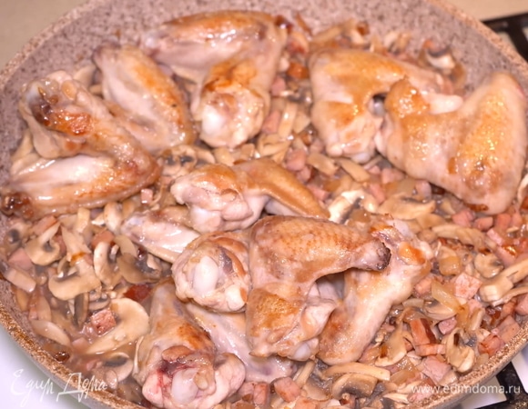 Как только грибочки пустили много жидкости, возвращаем на сковороду обжаренные крылышки. Пусть они пропитаются грибным соком и ароматом.