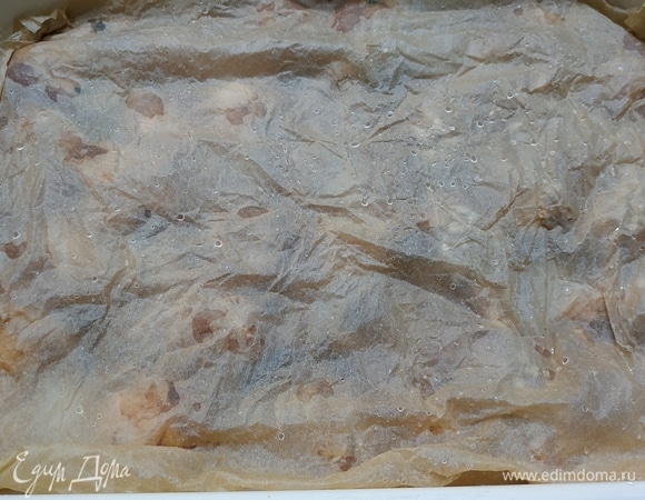 Лист пергаментной бумаги сомните в руке и смочите хорошо водой. Накройте куриные крылья и поставьте запекаться в духовку при температуре 180°C на 45–50 минут до готовности.