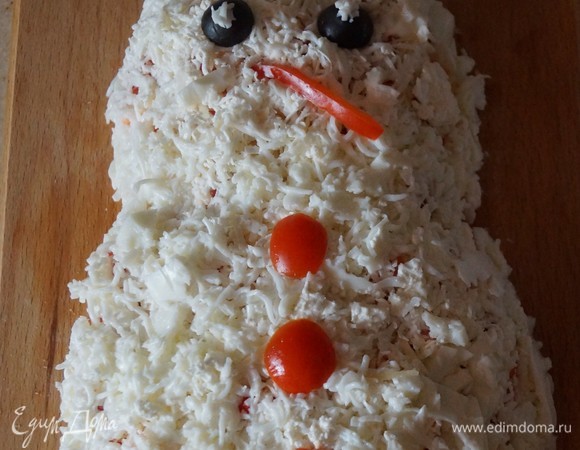 Далее нужно посыпать салат тертым пармезаном, мягким сыром, сверху натереть яичный белок. Украсить «глазками», «пуговками» и «ротиком» из оливок, перца и помидоров.