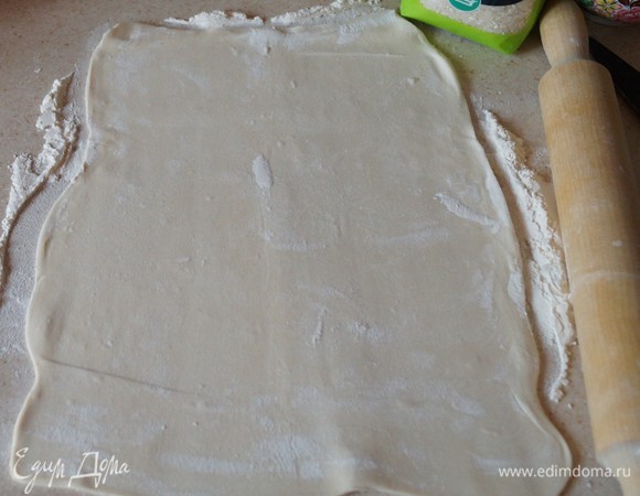 Готовое слоеное бездрожжевое тесто разморозить до комнатной температуры и раскатать. 200 г риса промыть в холодной воде и варить в подсоленной воде до полуготовности. Промыть.