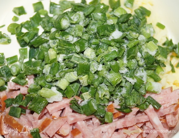 Картофель натрите на терке, выложите в чашу, добавьте яйцо, майонез, нарезанную соломкой колбасу. Влейте молоко, положите лук, все перемешайте.