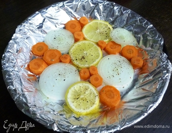 На дно формы положить колечки моркови, лука и лимона. Посолить и поперчить. Овощная подушка позволит рыбе не плавать в собственном соке.