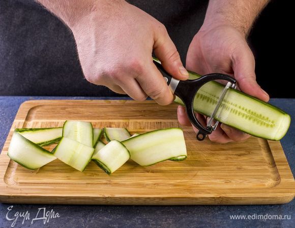 Овощечисткой нарежьте огурец тонкими длинными пластинками до семян.
