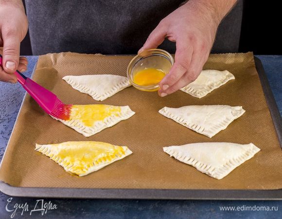 Смажьте все треугольники яичным желтком.
