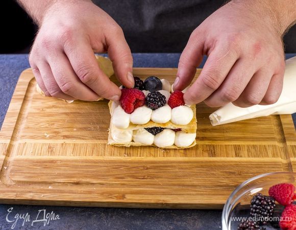 На последний корж выложите крем, украсьте ягодами и веточкой мяты.