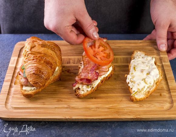 Выложите обжаренный бекон, базилик, помидры. Накройте второй половинкой круассана.
