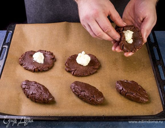 Затем сверните кружки в овальные формы. Выложите печенья на противень, застеленный пергаментной бумагой. Выпекайте в духовке при 180°C примерно 15 минут, до появления трещинок.