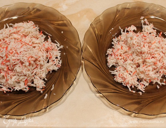 Крабовые палочки натираем на мелкой терке. Делим примерно на 2 одинаковые части.