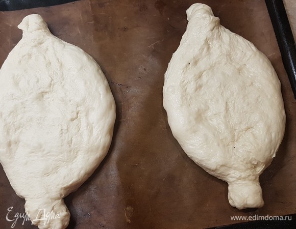 Духовку разогреть до 240°C. Тесто разделить на две части и сформировать продолговатые лодочки. По форме очень похоже на хачапури. Дать подойти 10. минут.