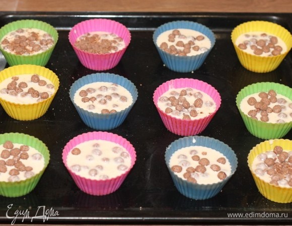 Формы для выпечки (у меня силиконовые) смазываем маслом и посыпаем панировочными сухарями. Помешивая, разливаем смесь по формочкам и посыпаем сверху оставшимися сухими снеками.
