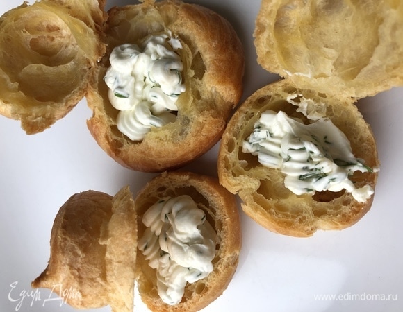 В творожный сыр добавить измельченные чеснок и укроп, массу поместить в кондитерский мешок и начинить профитроли.