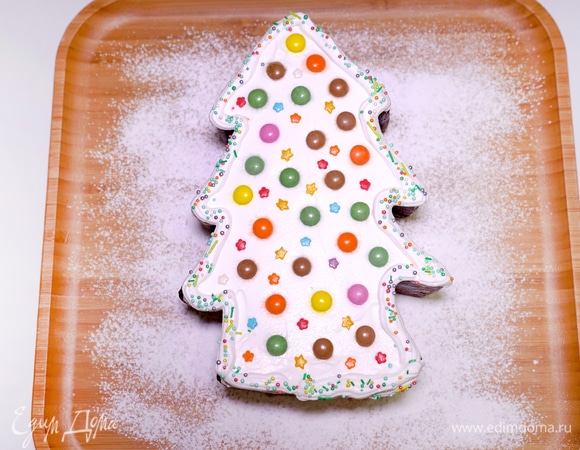Перекладываю остывшую выпечку на деревянную тарелку. Я посыпала ее сахарной пудрой. Украшаю поверхность елочки взбитыми сливками. Сверху на сливочную прослойку кладу разноцветные конфетки с шоколадной начинкой — это и есть наши елочные игрушки. Помимо этого, украшаю елочку кондитерскими посыпками в форме милых звездочек, чтобы наша выпечка засияла праздничными огнями.
