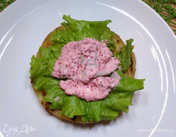 Собираем фишбургер. Булочку разрежем на 2 части. При желании можете обжарить булочку на сковороде гриль. Кладем салатные листья, немного соуса.