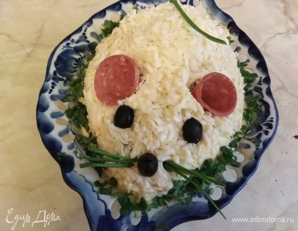 Из кусочков колбасы сделать ушки, свернув ее трубочкой. Маслины разрезать пополам, сделать глазки и носик. Из перьев лука сделать усы и хвост.