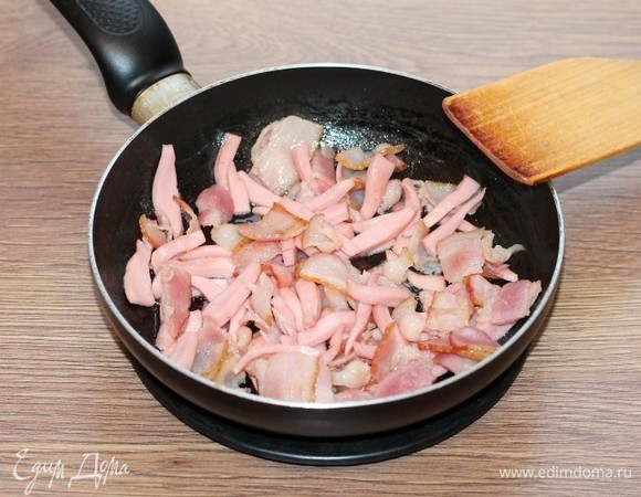 Выложить бекон в сухую сковороду и обжарить его на слабом огне до выделения смальца. Затем добавить кусочки колбасы и на среднем огне, помешивая довести мясную смесь до румяности.