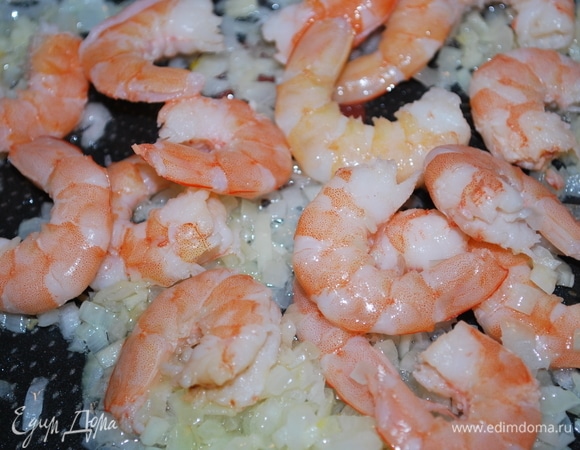К луку и чесноку добавьте почищенные креветки.