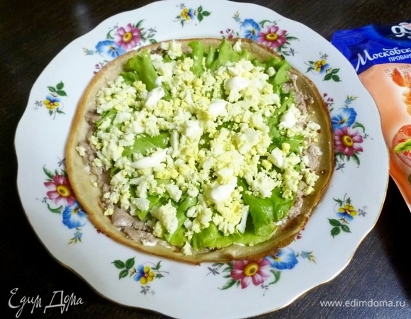 Блинчик смазать печенью минтая. На печень положить листья салата, посыпать нарезанной зеленью и измельченным вареным яйцом. Сверху — майонез ТМ «Московский провансаль», смажьте им начинку.