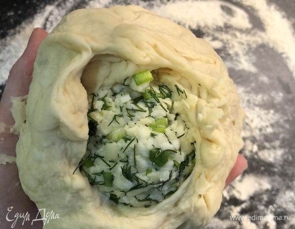 Тесто выложить на стол, посыпанный мукой, и разделить на 3 части. Сформировать шары. Далее каждый шар руками растянуть, внутрь положить сырный шар и края слепить.