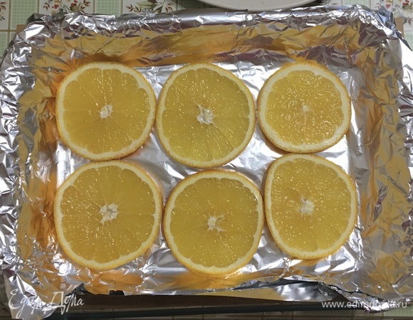 Выстелить фольгой форму для запекания, нарезать апельсин кружками и выложить на дно формы, делая подушку для курицы.