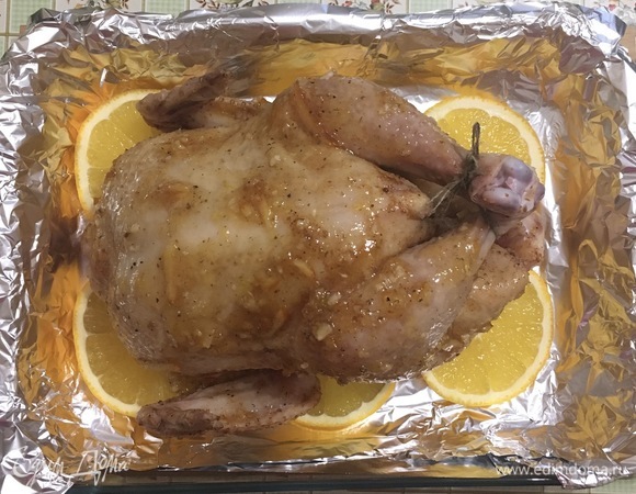 На апельсины выложить курицу и запекать при 190°C 1–1,5 часа (в зависимости от размера курицы), до готовности, часто поливая выделившимся соком.