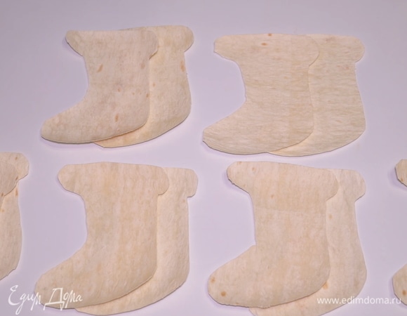 Из тонкого лаваша можно вырезать любые формы: например елочки, звездочки — что угодно. Но я вырезала с помощью бумажного трафарета небольшие носочки и сапожки. Нам понадобится 12 штучек.