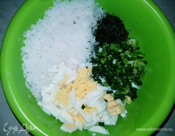 В чашку выкладываем отварной рис, отварные и нарезанные яйца (3 шт.), мелко нарезанные укроп и зеленый лук.