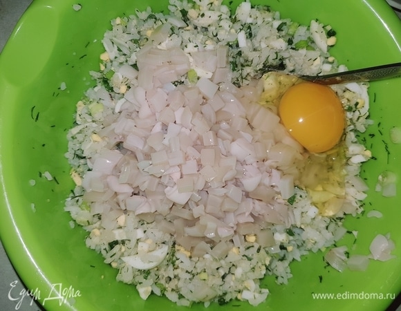 В чашку выкладываем нарезанные кальмары, сырое яйцо, солим, перчим и перемешиваем.