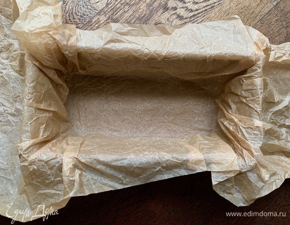 Духовку разогреть до 140°C. Глубокую форму застелить пергаментом так, чтобы можно было краями укрыть кекс.