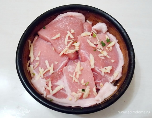 Мясо посолим и уложим в горшок. Чеснок нарежем и посыпем верх мяса.