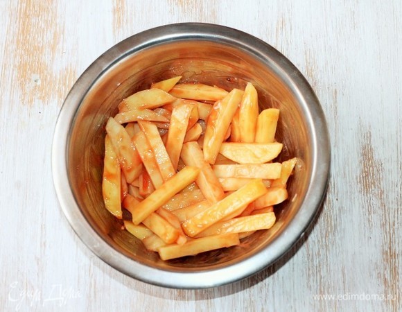 Смешиваем в миске прессованный чеснок, хлопья чили, кетчуп, соль и кукурузный крахмал. Добавляем картофель и хорошо перемешиваем.