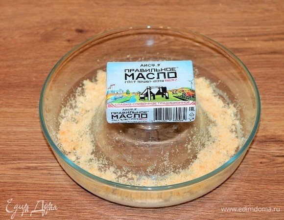 Форму для запекания щедро смазать сливочным маслом. Одно печенье измельчить на терке и обсыпать дно формы для выпечки.