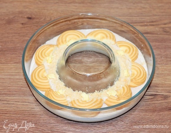 Оставшимся печеньем (половинками) украсить верх запеканки. Немного посыпать край середины измельченным печеньем. Разложить маленькие кусочки сливочного масла по кругу формы.