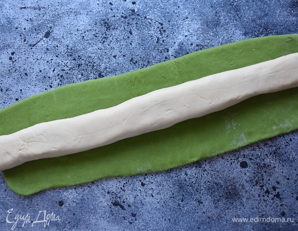 Из белого теста сформировать жгут. Зеленое тесто раскатать в прямоугольник и завернуть в него белое тесто, края закрепить. Отрезать от теста шайбочки толщиной 1 см и раскатать лепешки. Чтобы тесто не липло, посыпать поверхность смесью муки и крахмала.