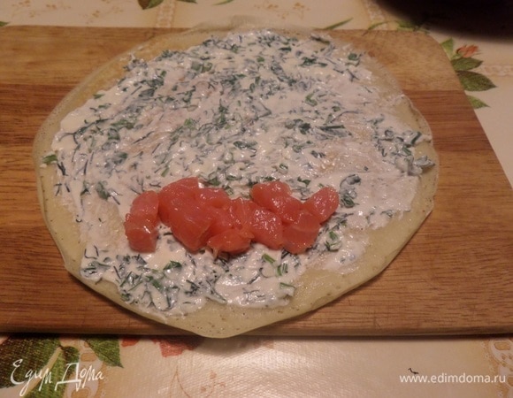 На блин выкладываем сырную смесь с зеленью и распределяем по всему блину. Выкладываем дорожку из рыбы.