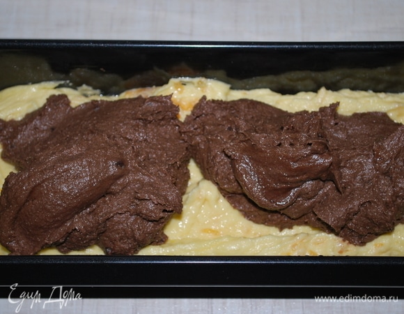 Сверху мандаринового теста распределите силиконовой лопаткой шоколадное тесто.