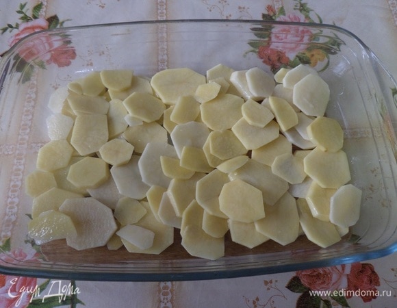 Пока маринуется рыба, моем и очищаем картофель. Нарезаем тонкими кружочками. Кладем в чашку, добавляем 1 ст. л. растительного масла и соль по своему вкусу. Перемешиваем. Выкладываем в глубокую форму для запекания.
