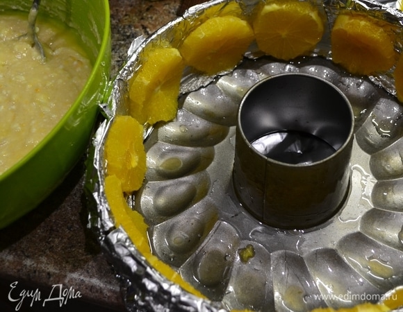 Подготовим форму для выпечки: по бортику проложить пергаментом или фольгой, смазать маслом. Разрезаем апельсин и кружками выкладываем по кругу бортика.