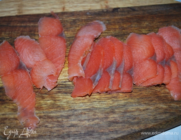 Нарежьте тонкими ломтиками красную малосоленую рыбу.