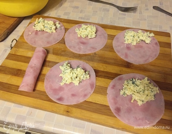 На каждый слайс ветчины кладем сырную массу и заворачиваем рулетом.