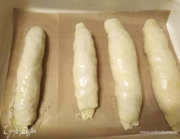 Противень застелить пекарской бумагой или ковриком для выпечки. Выложить рулеты. Поверхность смазать обильно яйцом.