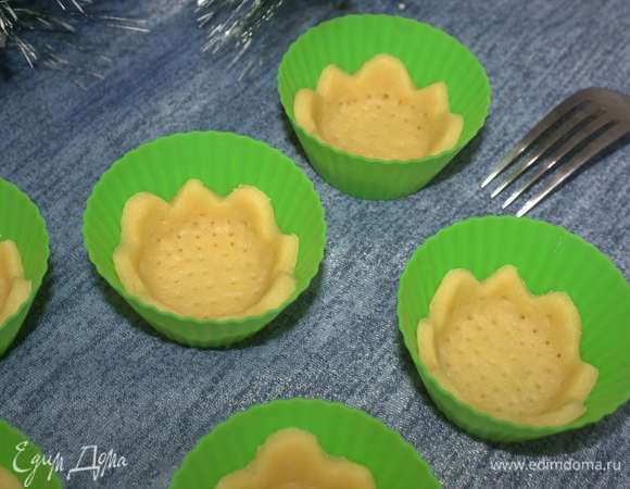 Укладываем в формочки. Вилкой делаем несколько проколов. Ставим в разогретую до 190°C духовку, выпекаем около 15 минут. Время выпечки будет зависеть от размера тарталеток и толщины их стенок. Признаком того, что их пора вынимать, станет золотистый цвет.