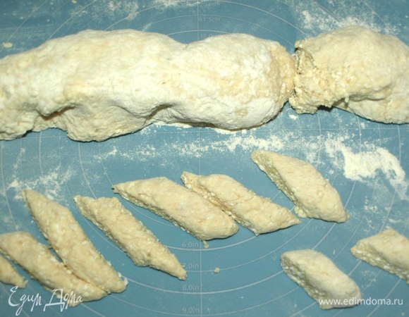 Постепенно добавляем просеянную муку. Муки может понадобиться меньше или больше, зависит от муки и жирности творога. На посыпанной мукой поверхности замешиваем мягкое тесто. Главное, не забить вареники мукой. Формируем тесто колбаской и наискосок нарезаем небольшие кусочки. Если тесто немного липнет к рукам, то руки припорошить мукой.