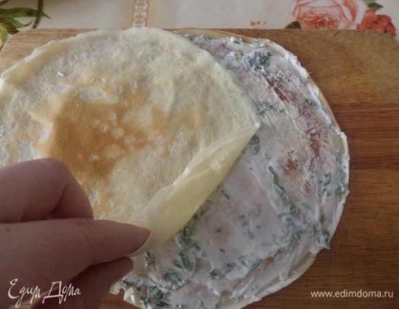 На разделочную доску кладем блин. На него выкладываем 2 ч. л. творожной начинки и распределяем по блину. Накрываем вторым блином и также распределяем творожную начинку.