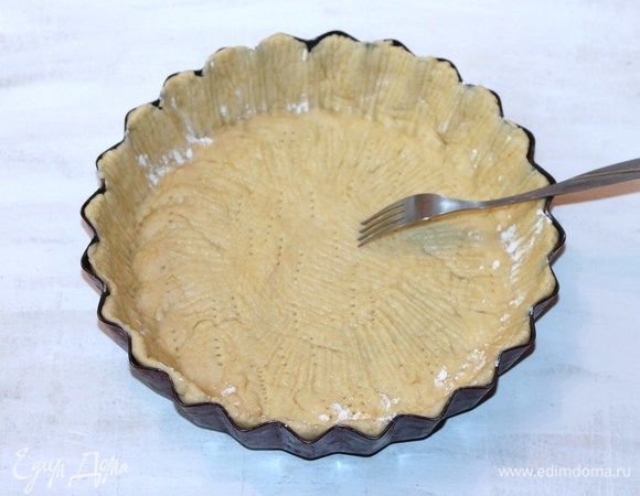 Формочку для выпечки диаметром 24–26 см с высокими бортиками застелить бумагой. Бумагу и стенки формы смазать маслом и обсыпать панировочными сухарями или припылить мукой. Готовое тесто раскатать в пласт, выложить в форму, проколоть вилкой в нескольких местах и отправить в разогретую до 190–200°C духовку на 10 минут. Выпекать до полуготовности коржа.
