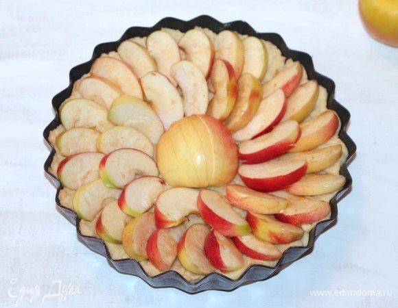 Полуготовый корж вынуть из духовки и распределить яблоки.